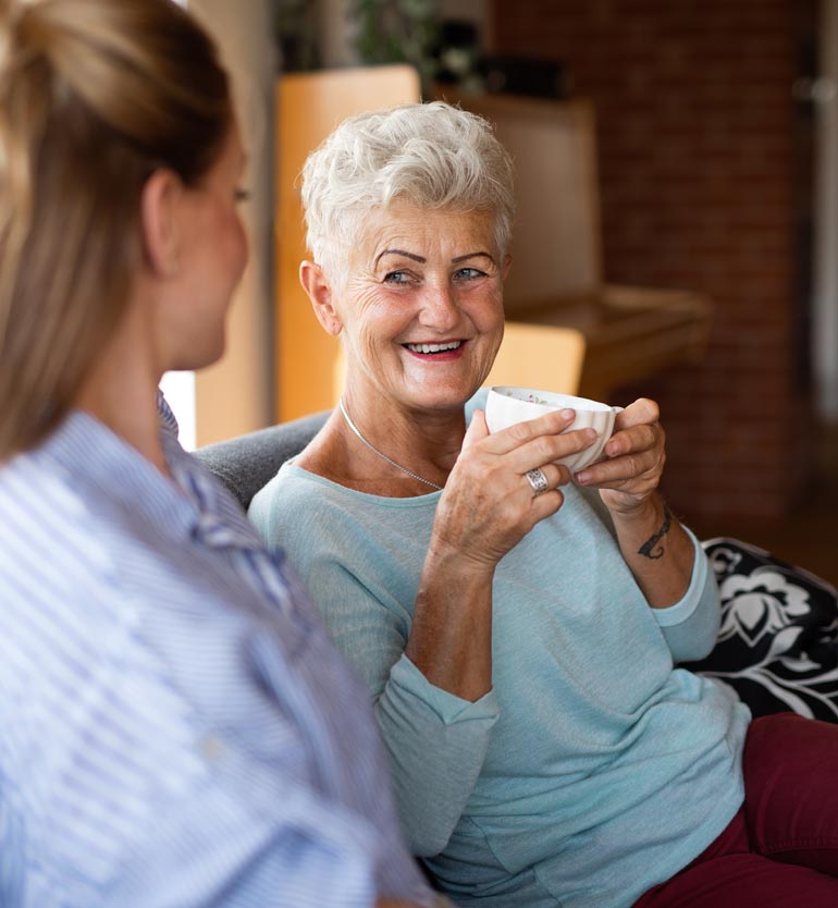 Cheerful senior woman enjoying a tea conversation with a younger team member